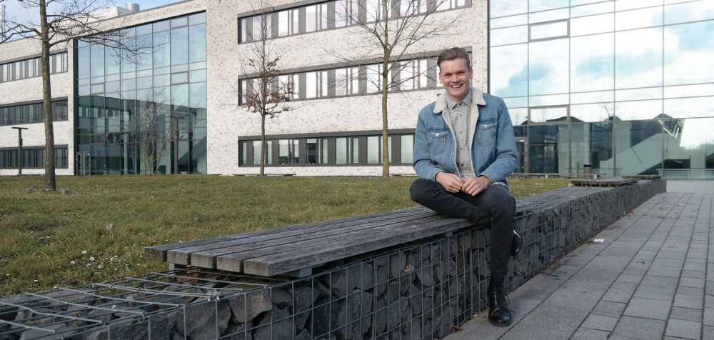 Student sitzt auf Mauer am Campus Hamm