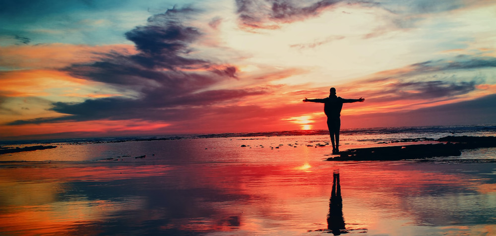 Person am Meer mit einem imposanten Sonnenuntergang